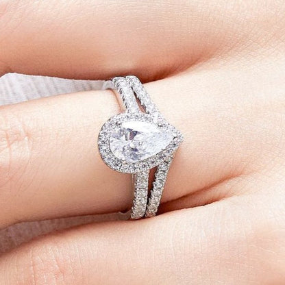 Silver ring with a heart-shaped center stone on a hand against a neutral background