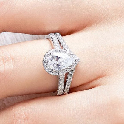 Silver ring with a heart-shaped center stone on a hand against a neutral background